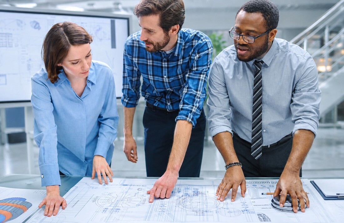 Engineering and technical services team reviewing technical drawings and discussing project requirements.