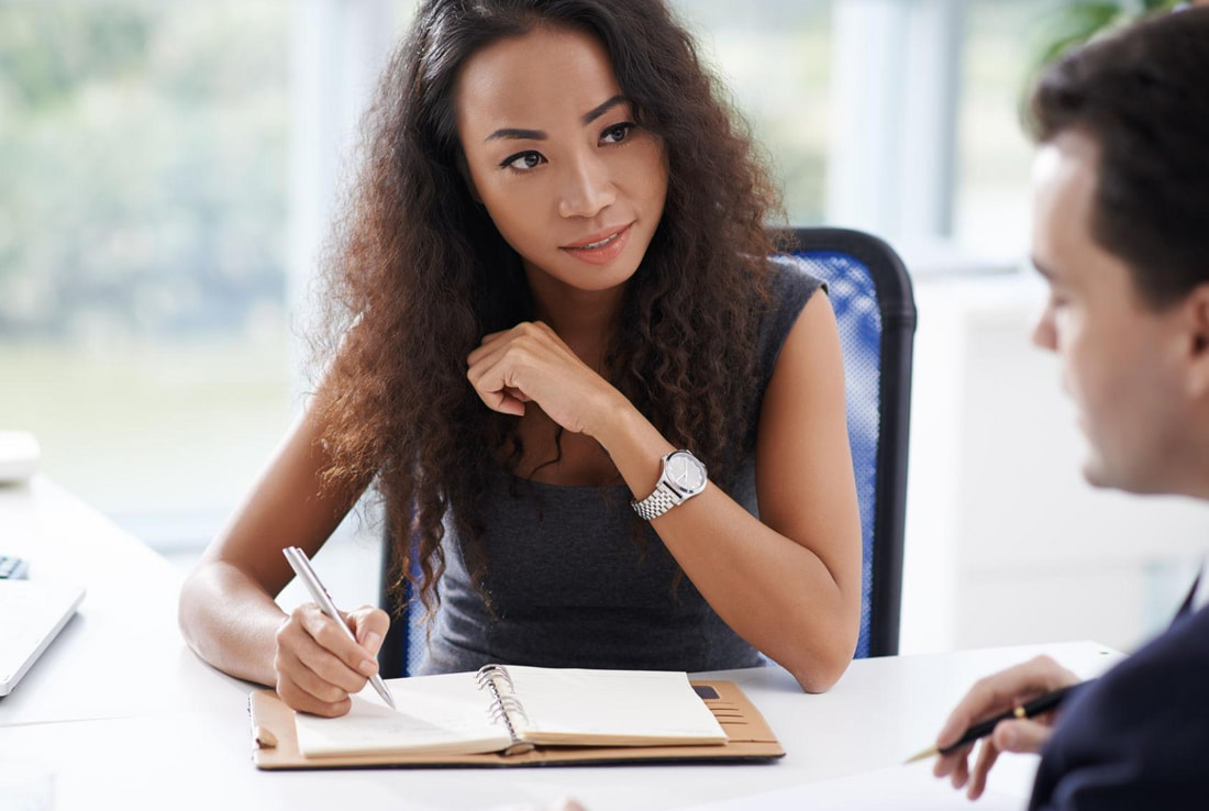 Professional adviser listening to a client and taking notes during a business discussion.